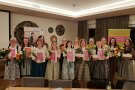 Personengruppe mit Urkunden und Blumen in einem Raum