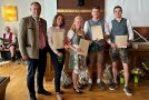 Fünf Personen, vier davon halten ein Zeugnis