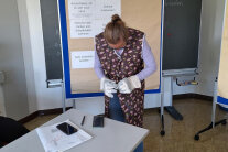 Person mit Arbeitshandschuhen steht vor Tisch
