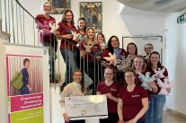Frauen halten einen großen symbolischen Scheck