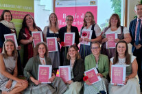 Personen halten jeweils ein pink bedrucktes Papier in Händen