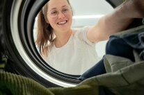 Frau steckt Wäsche in eine Waschmaschine
