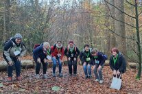 7 Personen stehen in Hocke im Wald