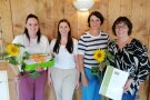 Vier Damen stehen zusammen mit Urkunde, Sonnenblume und Geschenk