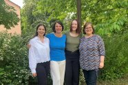 Vier Frauen stehen lachend vor einem Baum 