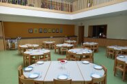 Die Cafeteria Biberbach ist ein großer Raum mit vielen Tischen und grünem Fußboden 