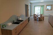 Vor niedrigen Kindertischen ist an der Wand eine Spüle für Kinder angebracht. 