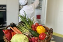 Großer Gemüsekorb mit Koch im Hintergrund