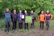 Mehrere Personen im Wald blicken in Kamera