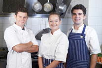 Portrait von Küchenchef und Personal am Herd stehend 