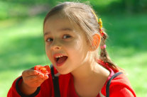 Mädchen führt Tomatenstück zum Mund 