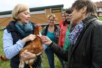 Bäuerin mit Huhn auf dem Arm im Gespräch mit einer Frauengruppe